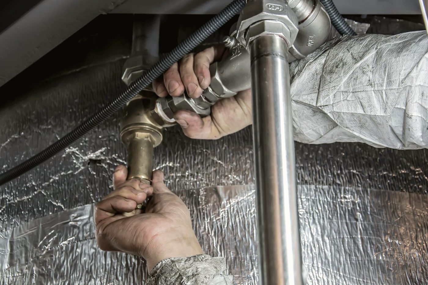 Hands installing brass and steel pipe fittings