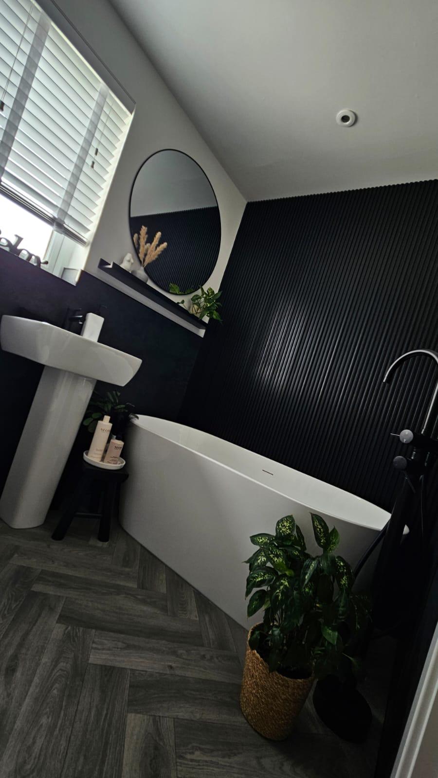 Fitted bathroom with a pedestal basin, freestanding bath and fluted wall panel