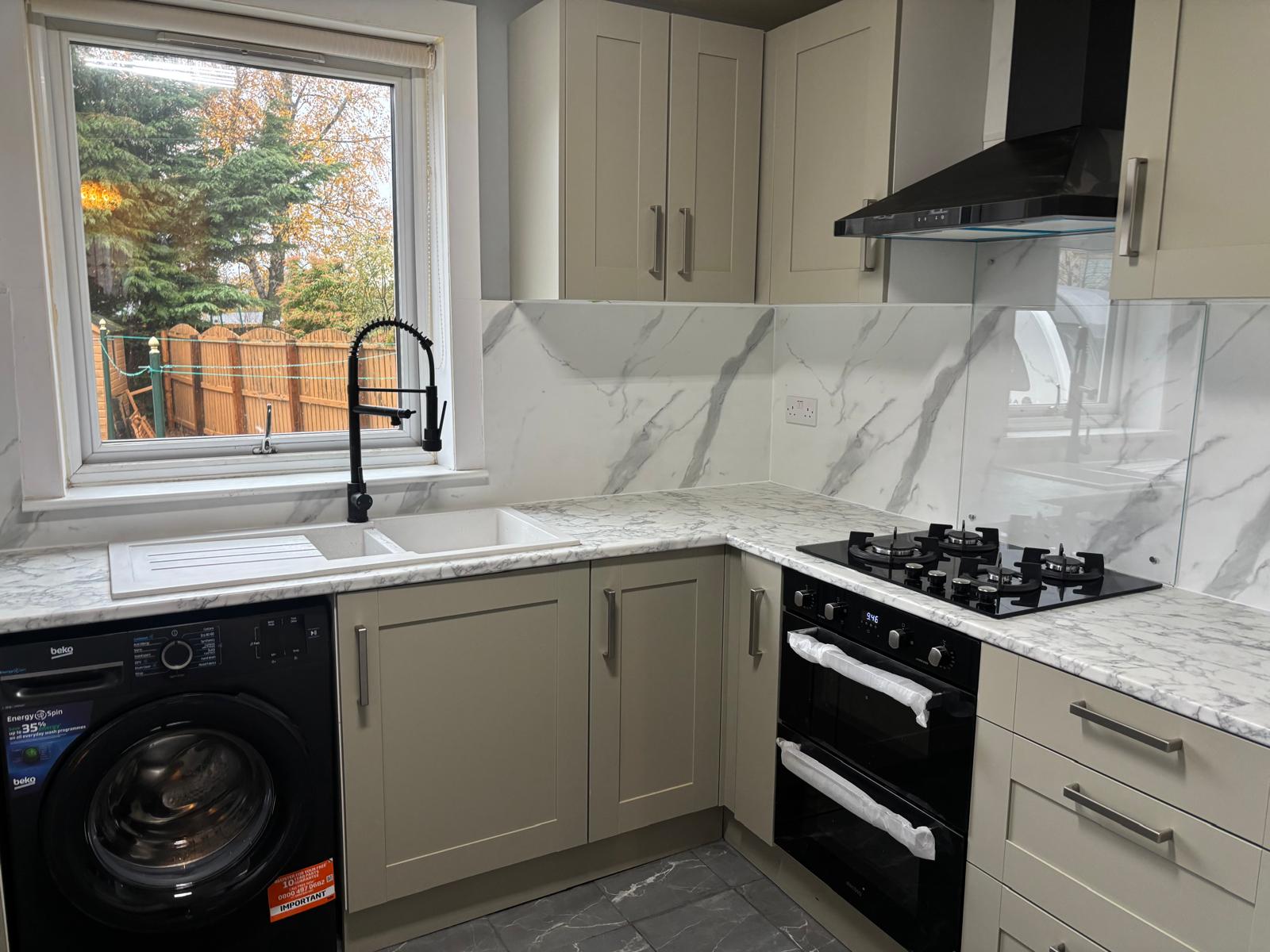Fitted grey kitchen with sink, gas hob and marble-effect splashback
