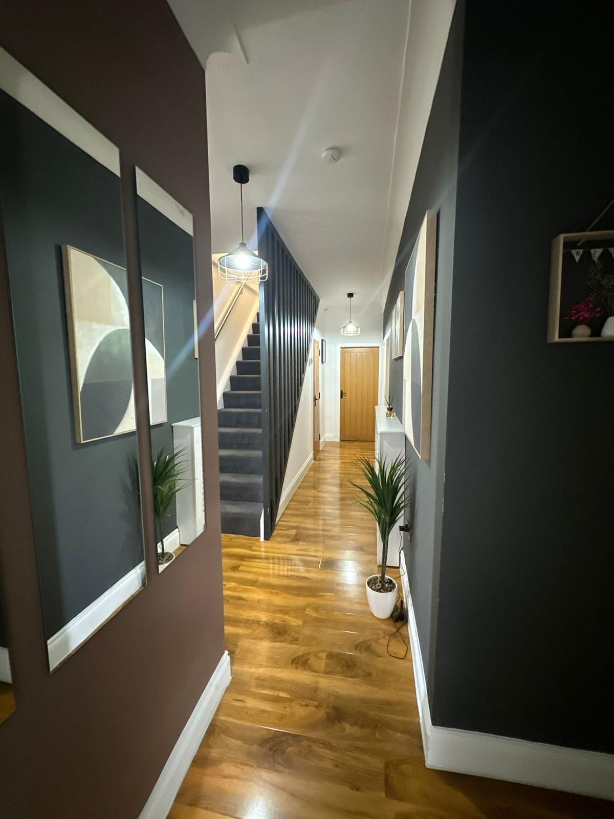 Renovated hallway with wood-effect flooring, painted walls and a carpeted staircase